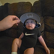 Preston joined the competition — help win amazing prizes! baby, child, infant, couch, sofa, clothing, onesie, cap, hand, indoor, person, sitting, sock, nike, curious, cute, brown, furniture, cozy, casual