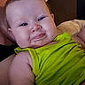 Nevaeh is registered to the contest to win money with this photo: baby, child, face, tongue, green_clothing, sleeveless, skin, cheeks, expression, smile, person, infant, closeup, portrait, lying_down, soft_surface, indoors, head, arm, cute