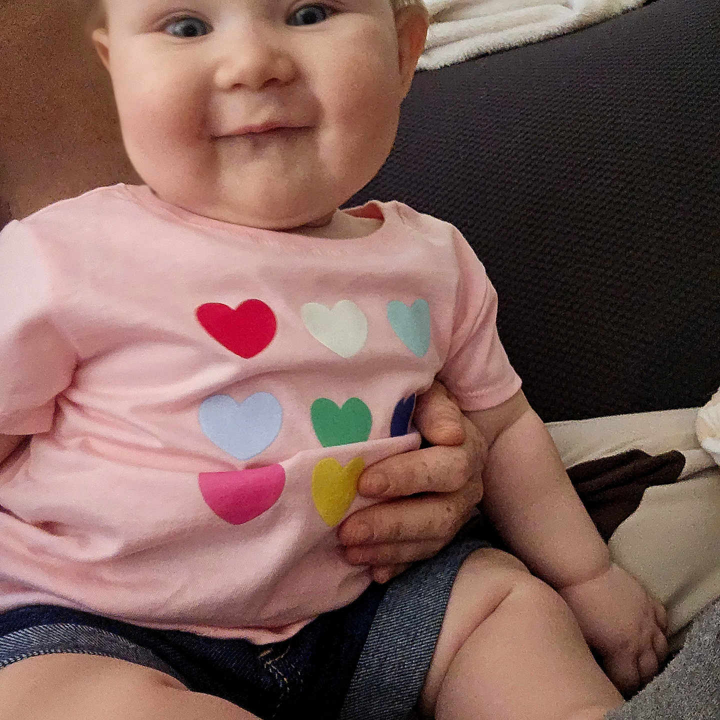 Nevaeh joined the competition — help win amazing prizes! baby, child, smiling, pink_shirt, hearts, sitting, indoor, couch, blanket, hand, person, portrait, cute, clothing, infant, happy, cozy, home, skin, face