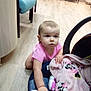 baby, child, pink_shirt, blanket, crawling, floor, indoor, wooden_floor, chair, furniture, curious, person, infant, car_seat, soft_toys, plaid, pattern, cute, young, exploring