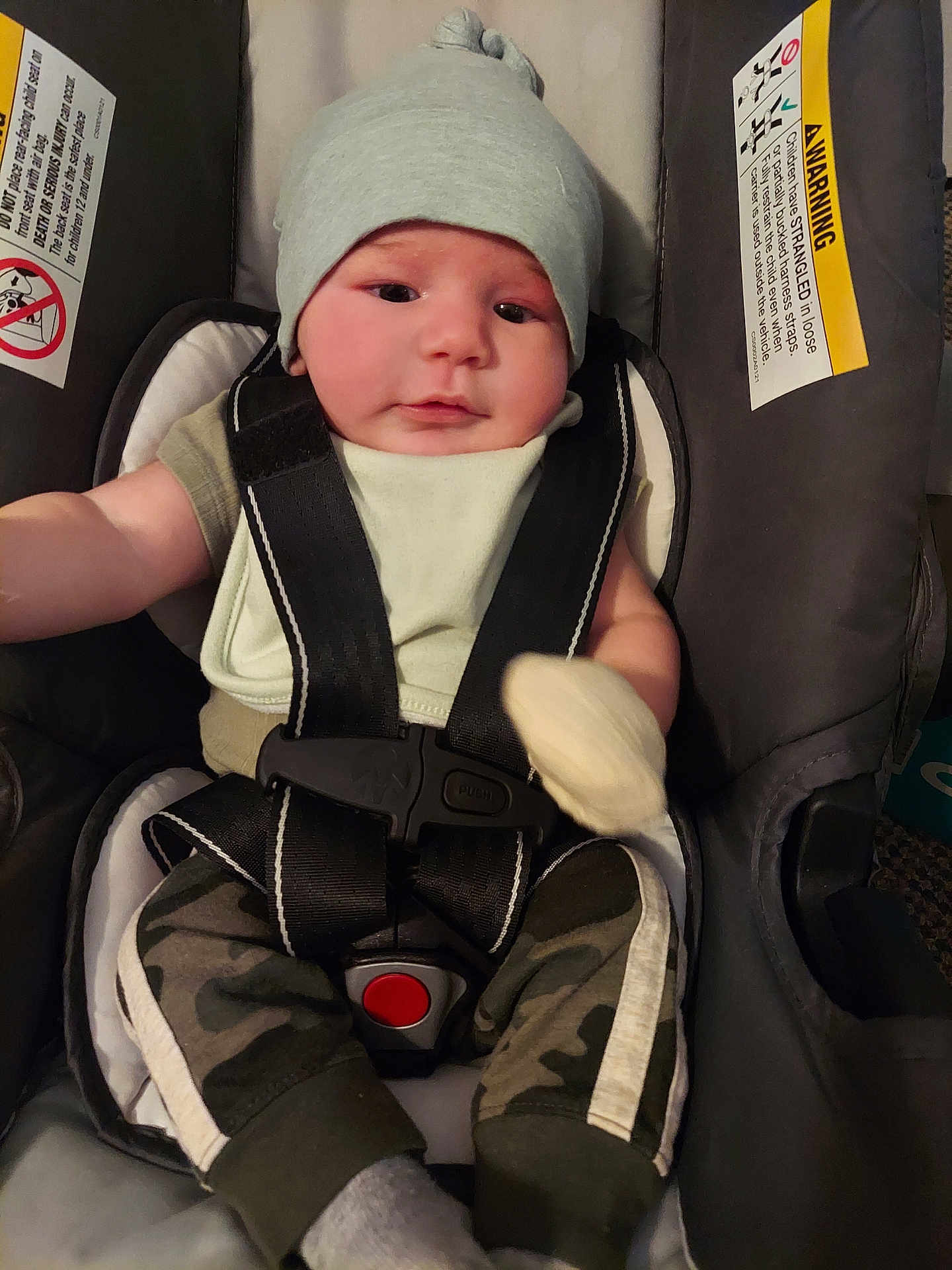 Joseph is registered to the contest to win money with this photo: baby, infant, car_seat, hat, clothing, straps, safety, child, cute, face, person, seat, camo_pants, sitting, indoors, young_child, headwear, baby_mitten, smile, comfort