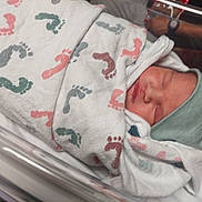 Joseph is registered to the contest to win money with this photo: newborn, baby, hospital, blanket, footprints, cap, sleeping, infant, bassinet, person, wrapped, closeup, cute, peaceful, child, resting, soft, hospital_room, newborn_care, medical