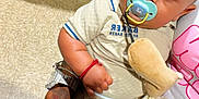 Zayvian joined the competition — help win amazing prizes! baby, pacifier, plush_toy, hand, watch, ring, bag, clothing, floor, person, lap, tattoo, skin, footwear, jeans, sitting, cute, indoor, accessory, bracelet