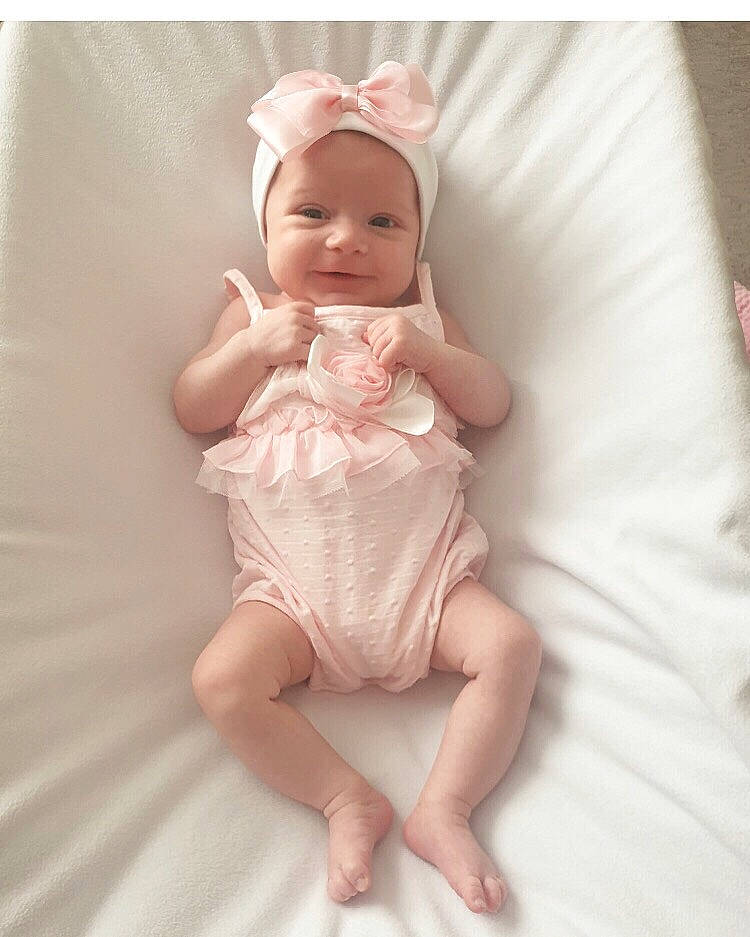 Abbie is registered to the contest to win money with this photo: baby, baby_products, blond, cheek, child, eye, head, headgear, headwear, joint, leg, person, pink, product, sitting, skin, textile, toddler, white