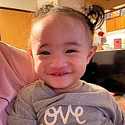 Delilah joined the competition — help win amazing prizes! toddler, child, smile, pigtails, hair, shirt, text, love_you, indoor, kitchen, clock, cabinet, person, happy, cute, portrait, face, baby, young_child, casual_clothing