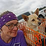 person, dog, purple_bandana, glasses, orange_crate, outdoor, vehicle, pet, canine, smile, casual_clothing, short_hair, earrings, leash, daytime, fence, headshot, portrait, animal, friendly
