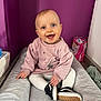 baby, smiling, blue_eyes, pink_sweatshirt, white_tights, black_shoes, cushioned_pad, indoor, purple_wall, child, happy, sitting, playful, cute, person, footwear, infant, clothing, portrait, room