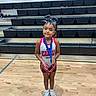 child, cheerleader, medal, gymnasium, bleachers, sportswear, bow, young_girl, smile, indoor, athlete, sport, floor, wooden_floor, white_shoes, posing, portrait, team, competition, award