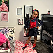 Sophia is registered to the contest to win money with this photo: child, girl, pose, mirror, bedroom, rug, skirt, cardigan, red_socks, hair_bows, poster, bed, pillow, mirror_reflection, floor, wall_art, carpet, furniture, smile, indoors