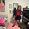 child, girl, pose, mirror, bedroom, rug, skirt, cardigan, red_socks, hair_bows, poster, bed, pillow, mirror_reflection, floor, wall_art, carpet, furniture, smile, indoors