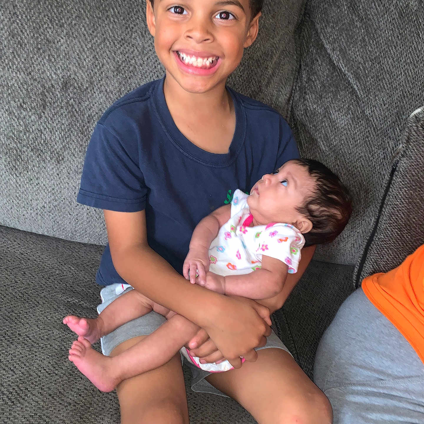 Brayden is registered to the contest to win money with this photo: baby, bodypart, chair, clothing, couch, cushion, face, furniture, happy, head, homedecor, newborn, people, person, photography, portrait, shorts, sitting, smile, t_shirt