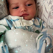 Davier is registered to the contest to win money with this photo: baby, infant, child, sleepy, portrait, face, eyes, smile, blanket, swaddle, onesie, clothing, bed, bedding, pillow, cozy, sparkles, filter, indoors, close_up