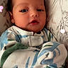 Davier is registered to the contest to win money with this photo: baby, infant, child, portrait, face, eyes, mouth, onesie, striped_clothing, sleeping_area, cushion, pillow, blanket, indoor, close_up, lying_down, cozy, heart_filter, photograph, adorable