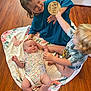 child, baby, toddler, playing, floor, blanket, wooden_floor, smiling, curly_hair, onesie, teal_shirt, sign, three_months, happy, indoors, family, candid, cute, people, sibling