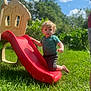 Luke is registered to the contest to win money with this photo: child, toddler, slide, playground, outdoor, grass, sunny, blue_sky, curly_hair, greenery, play, summer, nature, casual_clothing, barefoot, daylight, plastic_slide, backyard, person, fun