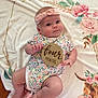 Valerie is registered to the contest to win money with this photo: baby, infant, child, headband, onesie, floral_pattern, blanket, wooden_sign, four_months, pink, cute, lying_down, soft_texture, pastel_colors, decorative, animal_print, curious, smiling, portrait, indoors