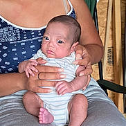 Lal Tapp is registered to the contest to win money with this photo: adult, baby, casual_clothing, child, closeup, comfort, cute, expression, hands, holding, indoor, infant, newborn, onesie, person, portrait, seated, skin, striped_clothing, wood_background