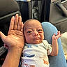 adult_hand, animal_print, baby, car_interior, casual, clothing, comfort, comparison, cute, expression, face, hand, infant, jeans, lap, person, seat, sitting, skin, small