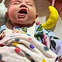 baby, laughing, blanket, polka_dot, floral_clothing, baby_seat, soft_toy, yellow_toy, pink_background, happy, infant, mouth_open, smiling, face, cheerful, child, cute, indoors, closeup, comfort