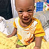 baby, child, infant, smiling, laughing, portrait, indoor, bedroom, bed, blanket, yellow_blanket, orange_clothing, colorful, sitting, happy, face, close_up, bedding, home, photography