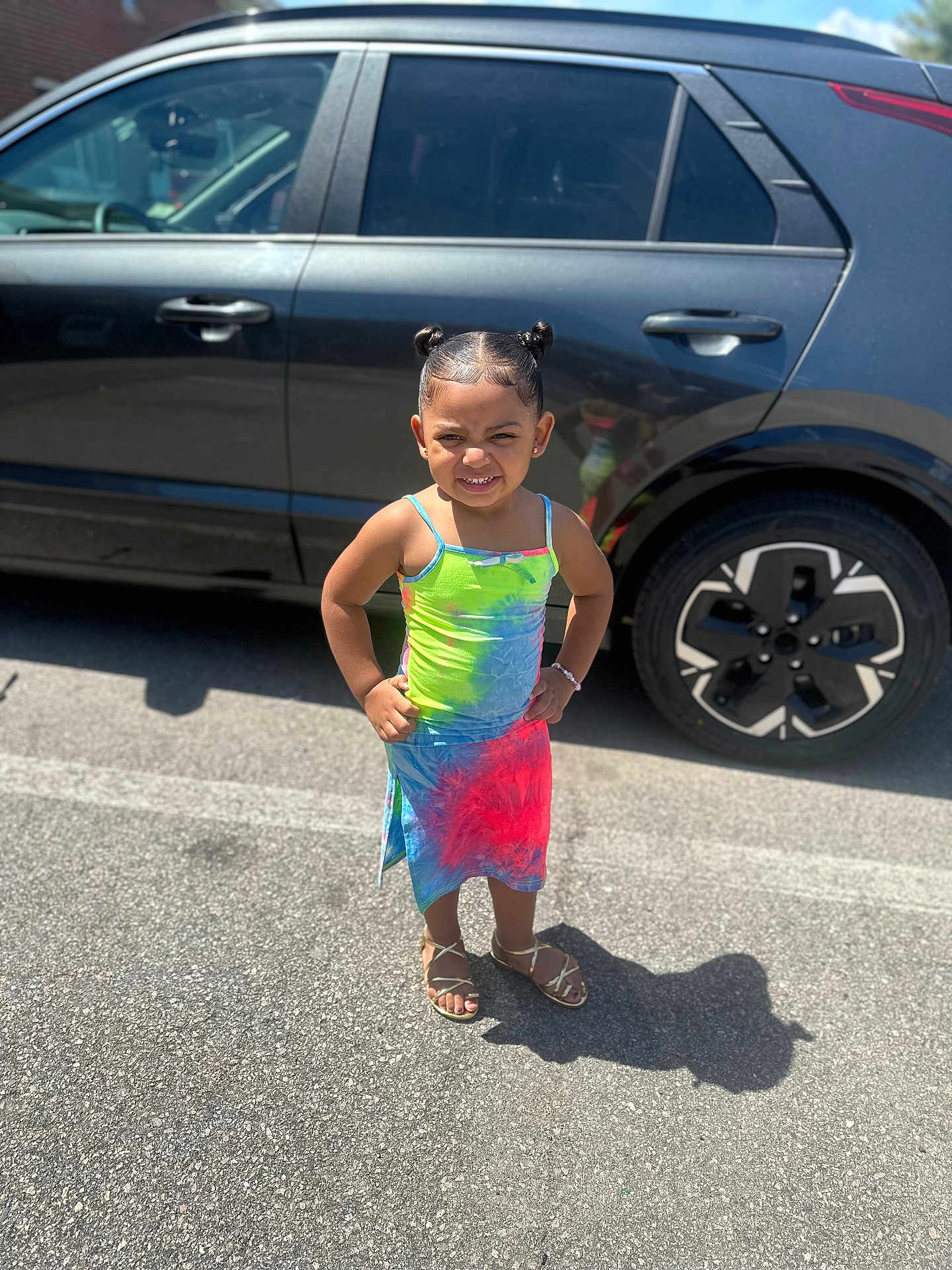 Dariahynis joined the competition — help win amazing prizes! child, girl, standing, colorful_dress, tie_dye, sandals, car, black_suv, parking_lot, shadow, sunlight, outdoor, asphalt, smile, hair_buns, bracelet, confident, person, summer, daytime