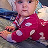 Ariel is registered to the contest to win money with this photo: baby, child, infant, polka_dot, pink_clothing, bed, blanket, pillow, indoor, portrait, cute, face, hands, lying_down, cozy, young_child, person, looking, curious, home