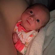 Evelynn joined the competition — help win amazing prizes! baby, infant, blanket, arm, clothing, sleepwear, face, skin, person, newborn, cozy, snug, curious, indoor, portrait, soft, looking_up, warm_light, resting, closeup