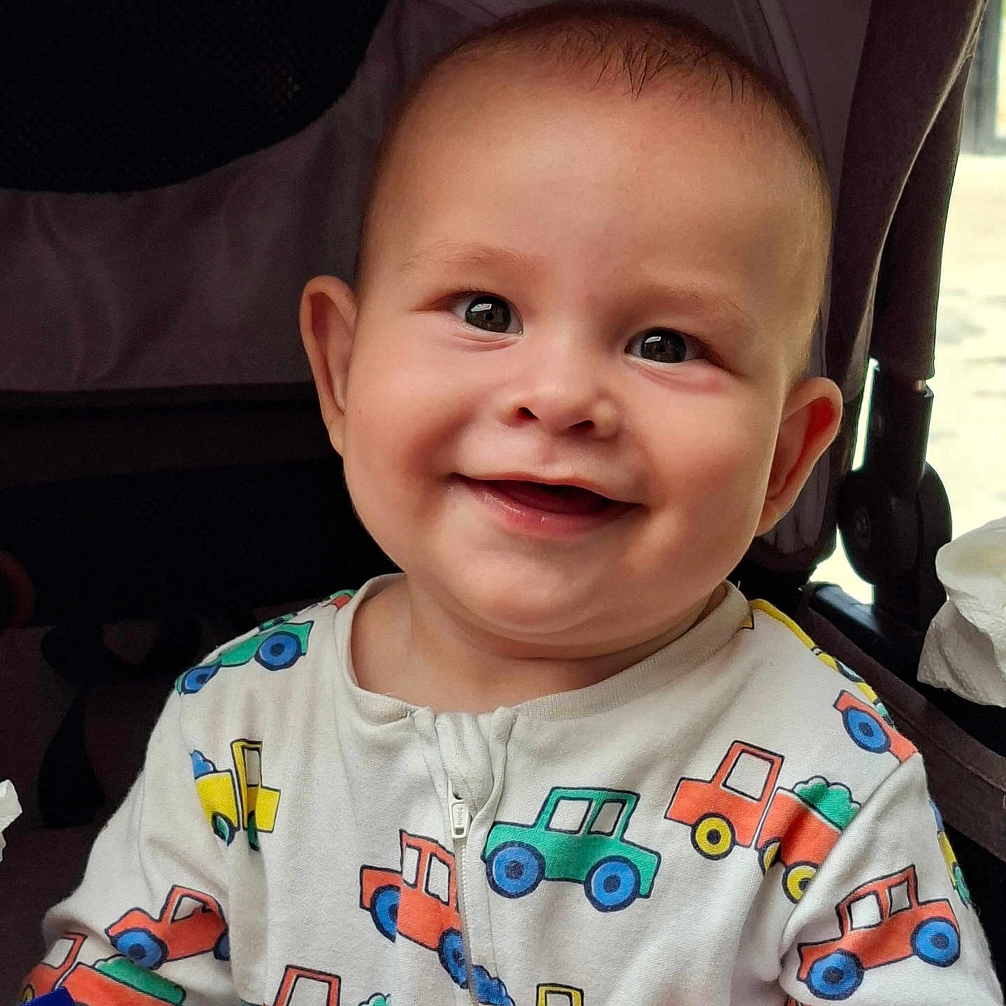 Robert joined the competition — help win amazing prizes! baby, bright, child, closeup, clothing, cute, expression, face, hand, happy, indoor, infant, joyful, onesie, person, seated, smile, soft_toy, stroller, trucks