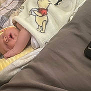 Riker is registered to the contest to win money with this photo: baby, sleeping, blanket, winnie_the_pooh, pillow, remote_control, bed, indoor, cozy, infant, child, resting, soft, comfort, cute, person, young_child, peaceful, nap, home