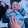 baby, child, hand, onesie, shark_pattern, bed, blanket, smile, face, fingers, manicure, nails, clothing, infant, person, indoor, cute, toddler, comfort, resting