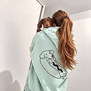 Bill participe au concours pour gagner de l'argent avec cette photo : dog, dachshund, puppy, brown_dog, pet, animal, person, woman, long_hair, ponytail, hoodie, mint_green, cartoon, dog_design, indoor, portrait, shoulder, carrying, white_wall, fashion