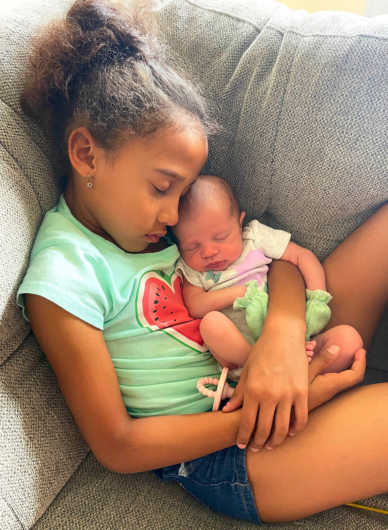 Emma is registered to the contest to win money with this photo: baby, cheek, child, comfort, eye, facial_expression, gesture, grass, hairstyle, happy, head, human_body, interaction, lap, mammal, people_in_nature, person, skin, thigh, toddler