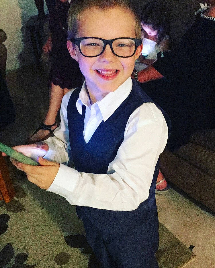 Kilby is registered to the contest to win money with this photo: child, cool, costume, eyewear, fictional_character, formal_wear, fun, glasses, joy, outerwear, person, smile, suit, tuxedo, vision_care
