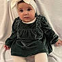 baby, child, white_bow, headband, green_dress, velvet, sitting, blanket, white_tights, soft_background, curious_expression, indoor, footwear, brown_shoes, cute, portrait, infant, chubby_cheeks, long_sleeves, hands