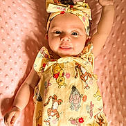 Amaya joined the competition — help win amazing prizes! baby, infant, child, smiling, winnie_the_pooh, headband, yellow_clothing, pink_blanket, curly_hair, cute, raising_arm, lying_down, soft_texture, playful, portrait, happy, indoors, closeup, one_person, baby_girl