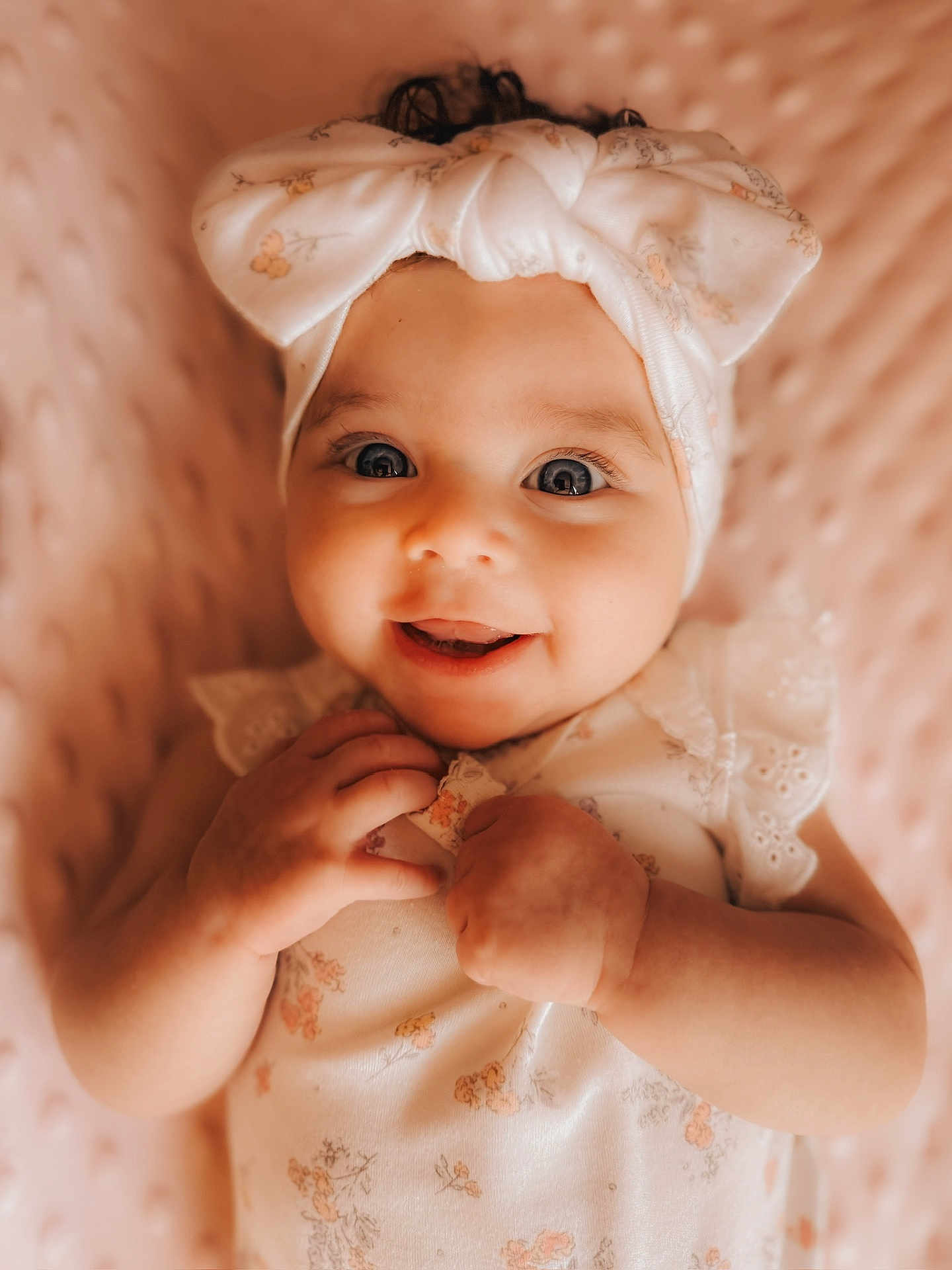 Amaya is registered to the contest to win money with this photo: baby, infant, smiling, headband, bow, cute, portrait, closeup, child, happy, pink, blanket, soft, texture, clothing, hands, face, eyes, skin, lying_down
