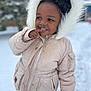 child, winter_clothing, hood, snow, outdoor, cold_weather, jacket, portrait, curly_hair, playful, pink_pants, polka_dots, smile, face, finger_on_lips, young_child, nature, daylight, casual, cute