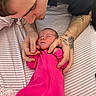 Ayla is registered to the contest to win money with this photo: newborn, baby, infant, sleeping, pink_onesie, onesie, adult, hands, tattoos, parent, cradling, bed, striped_bedding, blanket, cozy, indoor, portrait, family, peaceful, photography