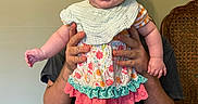Evangeline joined the competition — help win amazing prizes! baby, child, smiling, happy, female, bow, colorful_clothing, floral_pattern, ruffles, hands, adult, indoor, chair, wall, person, sitting, cute, portrait, headwear, playful