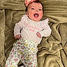 baby, infant, smiling, bow, pink_bow, blanket, floral_pants, cute_outfit, happy, lying_down, child, face, person, clothing, fabric, soft_texture, indoors, portrait, toddler, apparel
