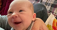 Dakota is registered to the contest to win money with this photo: baby, smiling, towel, hand, bed, blanket, plaid, red_throw, indoor, person, infant, happy, cozy, napping, skin, head, cute, newborn, family, comfort