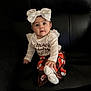 Alaia is registered to the contest to win money with this photo: baby, child, infant, white_bow, sitting, black_couch, long_sleeve_shirt, colorful_pants, sock, cute, indoor, portrait, curious, small_hand, big_eyes, clothing, leather_furniture, young_child, adorable, playful