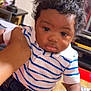 Tylee is registered to the contest to win money with this photo: baby, child, striped_shirt, polo_shirt, jeans, indoor, hand, person, curly_hair, furniture, lamp, table, casual_clothing, portrait, young_child, cute, holding, skin, face, expression