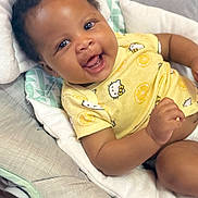 Azalea joined the competition — help win amazing prizes! baby, smiling, infant, yellow_onesie, cartoon_print, cushion, baby_seat, happy, child, portrait, indoor, cute, skin, face, expression, comfort, clothing, playful, joy, relaxing