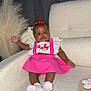 Azalea joined the competition — help win amazing prizes! baby, child, pink_skirt, white_top, red_bow, socks, couch, indoor, home_decor, plush, smiling, cute, infant, furniture, portrait, sitting, wall, curtain, decorative_grass, bracelet