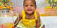 Azalea is registered to the contest to win money with this photo: baby, child, smiling, yellow_dress, white_bow, pitcher, lemon, strawberry, blanket, sitting, happy, indoors, portrait, cute, refreshing_drink, flower, curtains, window, decor, playful