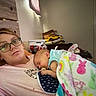 John joined the competition — help win amazing prizes! woman, baby, blanket, glasses, indoor, bed, couch, sleeping, toy_car, room, furniture, pacifier, casual_clothing, head, relaxation, person, nap, comfort, home, portrait