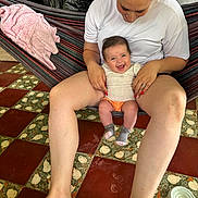 Luna joined the competition — help win amazing prizes! baby, blanket, clothing, cozy, face, floor, foot, hair, hammock, hand, happy, indoor, pattern, person, red_nails, ring, sitting, smile, tile_floor, woman