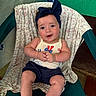 baby, child, smiling, headband, bow, sitting, chair, clothing, tank_top, shorts, indoor, fabric, pattern, green_wall, floor, person, cute, happy, portrait, skin