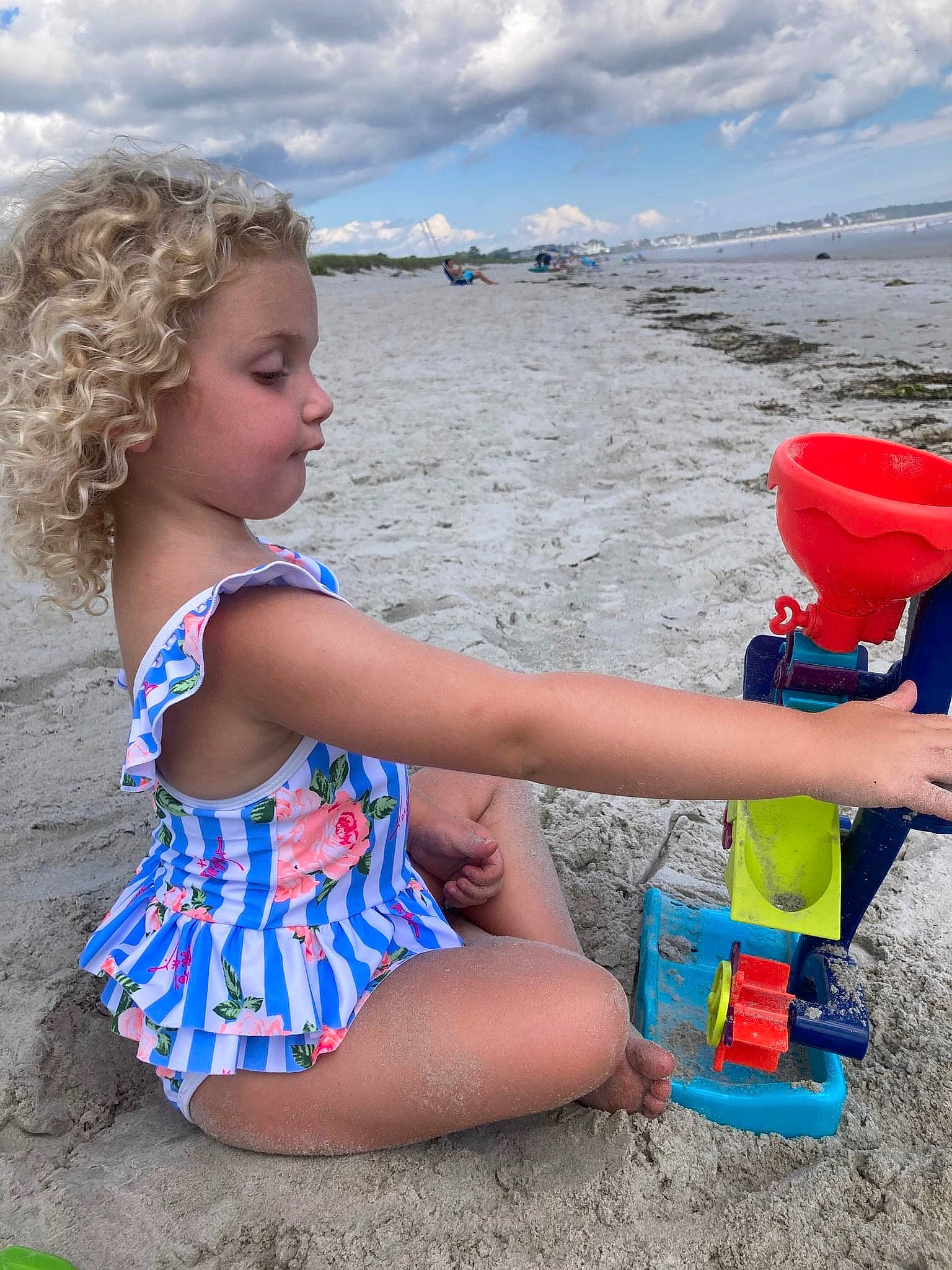 Evie is registered to the contest to win money with this photo: beach, body_of_water, child, cloud, electric_blue, fun, hat, human_leg, leisure, people_in_nature, people_on_beach, person, sand, shore, shorts, sky, summer, swimwear, thigh, toddler